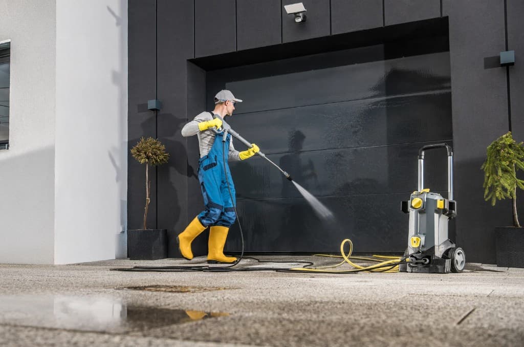 Worker pressure washing a large commercial garage door