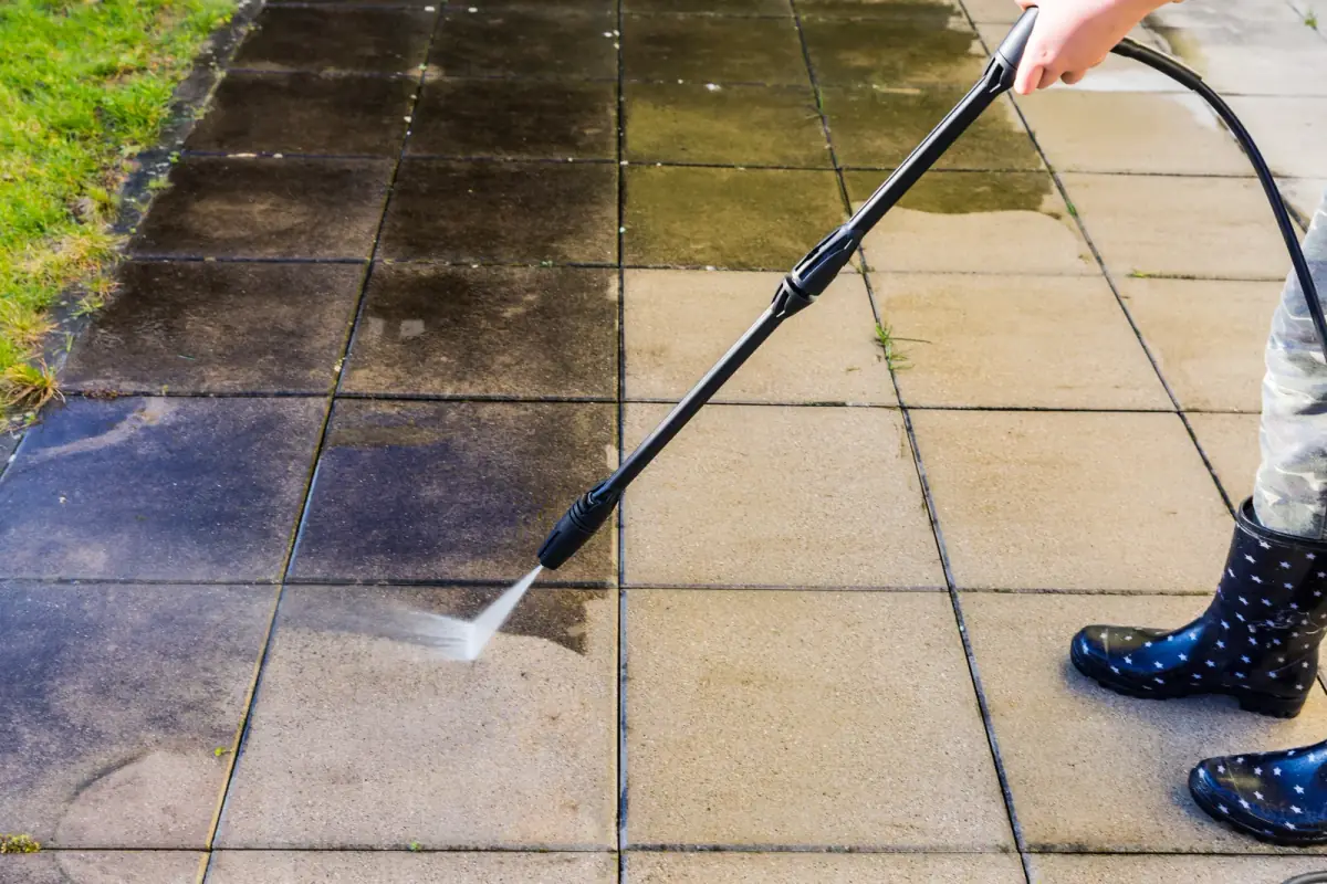 Pressure washing restoring patio pavers to a clean finish
