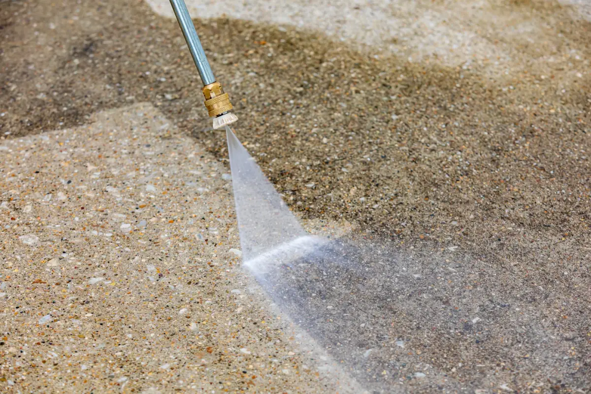 Close-up of pressure washing restoring a concrete driveway surface